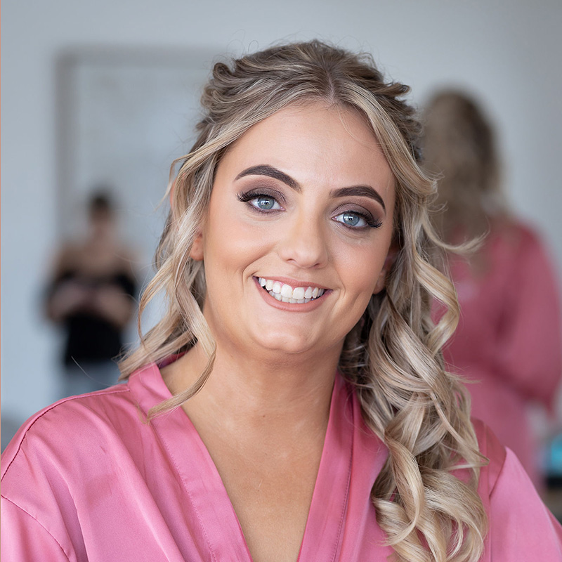 woman with nice makeup wearing pink gown smiling at camera